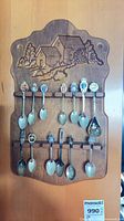 Full view of carved wood rack holding approx 14 souvenir teaspoons