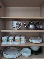 Cupboard shelves showing mugs, teapot, plates, bowls