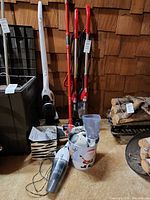 Group of two stick vacuums with handheld unit, dust cups, tools and cord