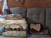 Stack on couch showing afghan, linens, pillow, blankets