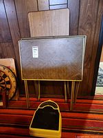 TV tray table front view showing veneer top and folded gold metal legs, scale at base