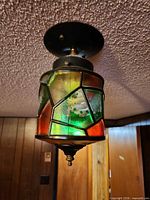 Front angle of ceiling fixture showing glass panels and metal canopy