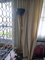 Full view of floor lamp beside window showing bowl shade, triple rods, base
