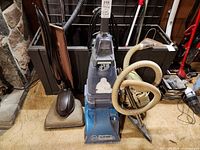 Overall lot showing Hoover SteamVac, vintage upright vacuum, hose and accessories