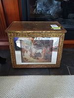 Front view of gold gilded decorative storage box showing glass panel with printed scene