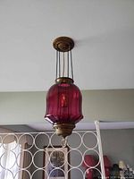 Full view of pendant light hanging from ceiling showing shade, chains, and canopy