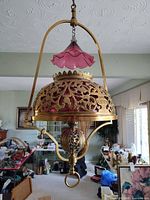 Full view of brass pendant light with cranberry glass and pink shade
