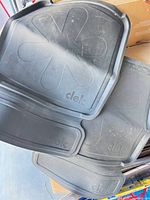 Four black Clek rubber seat protectors stacked, showing top surfaces