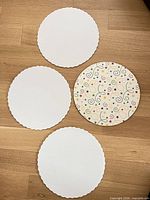Four round 10-inch scalloped cake boards; three white, one star-patterned