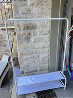 Full view of garment rack showing frame, top bar, shelves and hooks