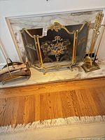 Overall view of fireplace accessories: screen, tool set on stand, log holder