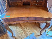 Front view showing overall form, cabriole legs, scalloped front, centre drawer