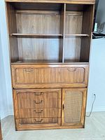 Full front view of tall secretary desk cabinet showing shelving, drop front, drawers and cane door