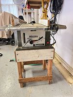 Makita 2708 table saw on wooden stand, full view