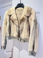 Full front view of cropped ivory mink fur jacket on hanger showing leather trim and buttons