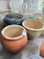 Three pots: terracotta ceramic, beige ceramic, dark green plastic