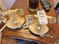 Both ivory rotary-style phones side by side on table