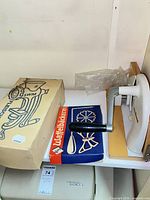 Shelf view showing boxed meat grinder, boxed rosette kit and white food mill on wood base