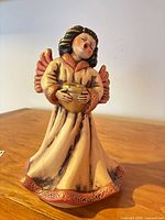 Front view of ceramic angel figurine holding gold candle cup