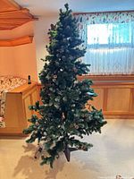 Full view of green artificial Christmas tree assembled on tripod stand