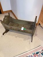 Full view of wooden doll cradle showing rocking runners, overall paint finish, size context