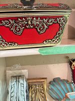 Ornate red storage box, packaged scroll plaques, gold corbel and turquoise shell plaque on shelf