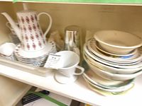 Overall lot showing coffee pot, dripper and stacks of dinnerware on shelf