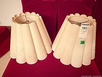 Pair of matching pleated scalloped bell lampshades on red background