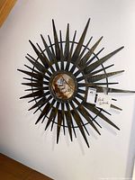 Front view of metal sunburst mirror showing spoke pattern and round glass center
