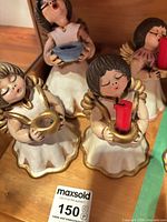 Front view of four ceramic angel candle holders showing colour, size and condition
