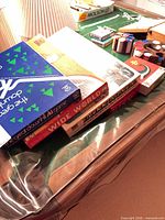 Stacked board game boxes including Wide World, other items on gaming table