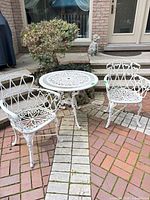 White cast aluminum bistro table and two matching chairs on patio