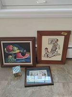 All three framed art pieces and photo cube on floor