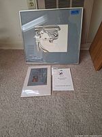 Overall view of framed portrait print and unframed signed print on floor