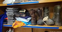 Shelf with grey wool sleeves, folded garments, three pairs boots