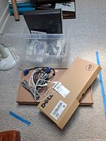 Overview of lot: clear tote with multiple keyboards, Dell keyboard boxes, cables visible