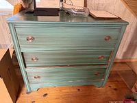 Full front view of teal painted three-drawer dresser