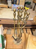 Full view of brass fireplace tool set on stand