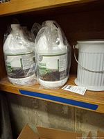 Four plastic gallon jugs of 30% vinegar beside white compost pail
