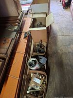Row of open boxes showing glass carboy neck, PVC fittings, metal can and miscellaneous hardware