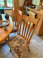 Front view of oak chair next to dining table, showing seat cushion and overall design