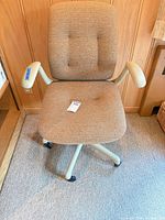 Front angled view of brown upholstered adjustable office chair with arms and casters
