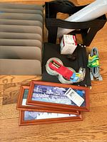 Entire lot showing framed photos, organizers, tape, wrap, extension cord, bulb, adapter