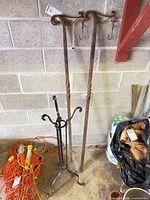 Full view of three metal plant stands leaning against wall