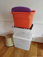 Stacked view of orange tote, clear bins, and beige foot stool