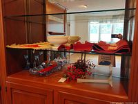 Overall view of textiles, serving bowl, candlesticks, tray and faux berries on shelving