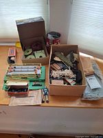 Overview of assorted Lionel train parts, wire spools, livestock platform, animal figures and boxes of small parts