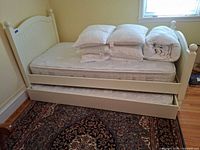 Overall view of white twin bed with trundle, mattresses and bedding