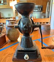 Front view of entire coffee grinder on wood base