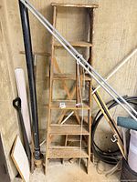 Full view of 6-ft wooden ladder leaning against wall with surrounding objects